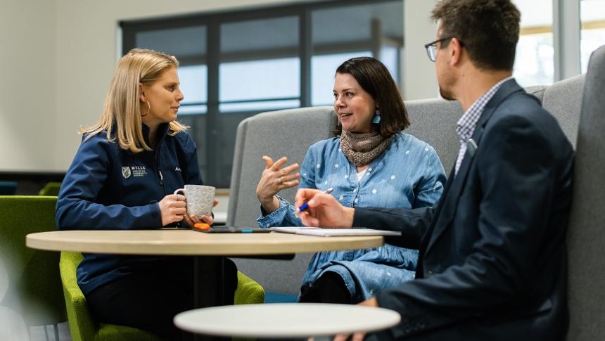 Three adults sitting in a professional setting in discussion
