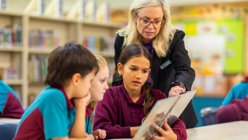 Three students and an adult reading a book