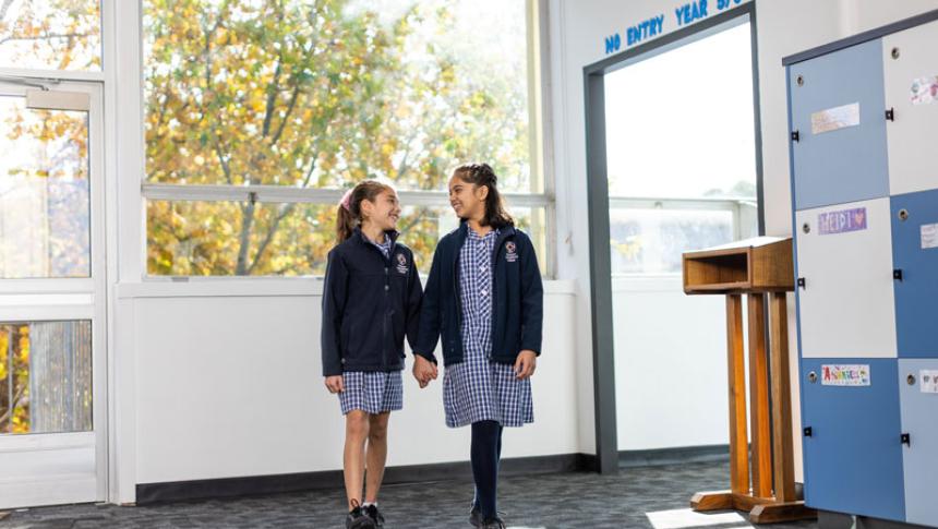 Two students walk through a school corridor. 