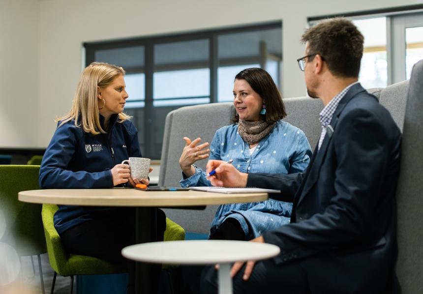 Three adults sitting in a professional setting in discussion